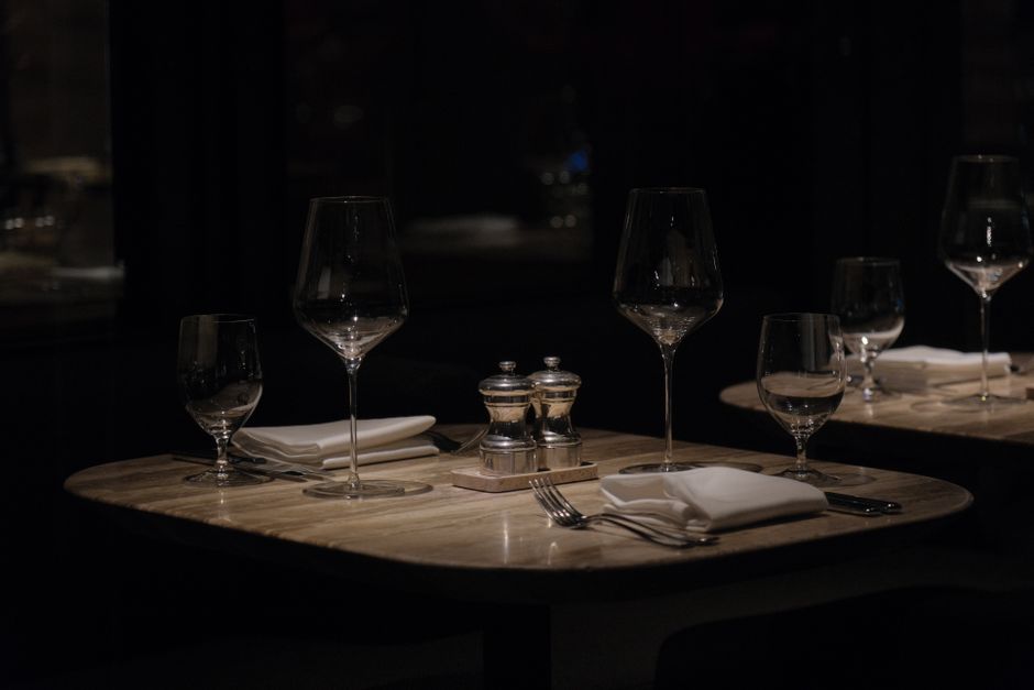 Dark atmospheric restaurant table setup with wine glasses and napkins