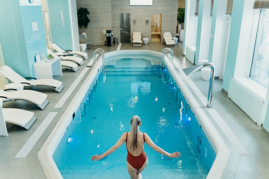 Woman preparing to enter an elegant indoor pool at a luxurious spa