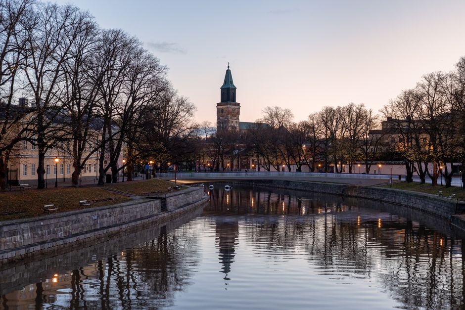 Turku Cathedral with bare trees reflecting on the river in Finland at dusk